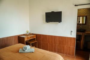 a bedroom with a bed with a television on the wall at De Olas Padang Padang Bali in Uluwatu