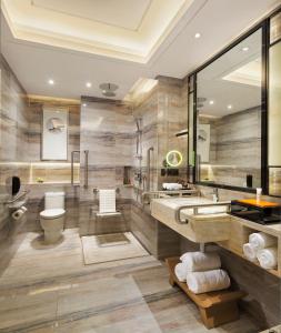 a bathroom with a sink and a toilet and a mirror at Hilton Zhuzhou in Zhuzhou