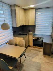 a kitchen with wooden cabinets and a table with chairs at Laivų gatvės apartamentai in Telšiai