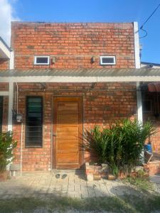 un edificio de ladrillo con una puerta de madera. en OYO 90910 Homestay D Lalang Inn, en Kuah
