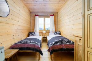 two beds in a log cabin with a window at Ski-in & Ski-out out Chalet Maria with amazing mountain view in Maria Alm am Steinernen Meer