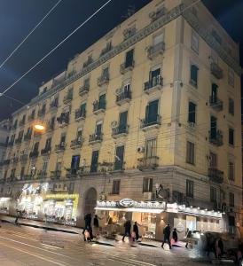 Un gran edificio con gente caminando frente a él. en Sunny Suite Napoli, en Nápoles