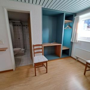 a room with a chair and a bathroom with a toilet at B&B Pension Rustica in Inden