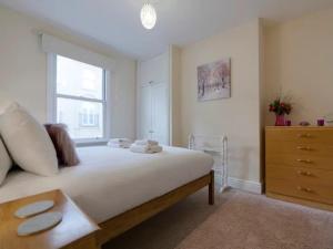 a bedroom with a large bed with a dresser and a window at Pass the Keys Modern and Spacious Terrace in Central Cambridge in Cambridge