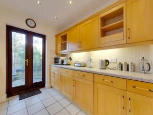 a kitchen with wooden cabinets and a large window at Pass the Keys Modern and Spacious Terrace in Central Cambridge in Cambridge