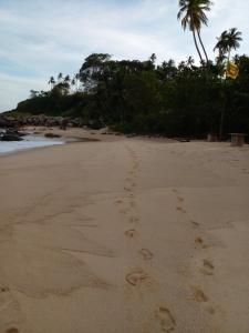 ein Paar Fußabdrücke im Sand am Strand in der Unterkunft Ruka Homestay in Tangalle