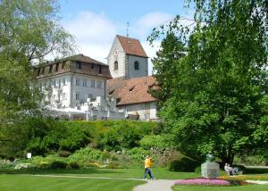 a person walking in a park in front of a building at Hotel Schloss Romanshorn in Romanshorn