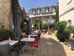 a row of tables and chairs with umbrellas in front of a building at Pleine Mer in Yport