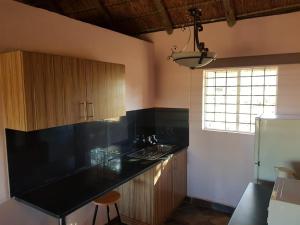 cocina con encimera negra y nevera en Lagai Roi Guesthouse, en Boshoek