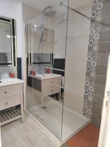 a glass shower in a bathroom with a sink and a toilet at Maison de village à maligny 89 in Maligny