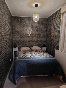 a bedroom with a bed and a brick wall at Maison de village à maligny 89 in Maligny