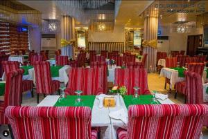 uma sala de jantar com cadeiras e mesas vermelhas e mesa de trabalho em Golden Tulip Hotel Port Harcourt -GTPH em Port Harcourt