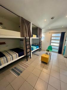タガンガにあるOcean Lovers Apartamentosの二段ベッド2台と黄色いスツールが備わる客室です。