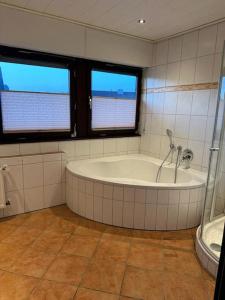 a bathroom with a bath tub and two windows at Große Personalunterkunft in Bad Bentheim in Bad Bentheim