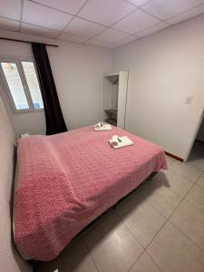 a bedroom with a bed with a pink blanket and two towels at Suite in Tres Arroyos