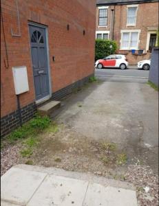 un parking vide à côté d'un bâtiment en briques avec une porte dans l'établissement Affordable Flats - Derby City Centre, à Derby