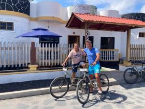 two men standing next to a bike in front of a building at La Casa de Joel in Puerto Villamil