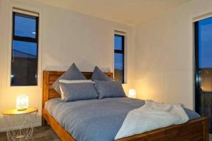 um quarto com uma cama com almofadas azuis e janelas em Lovely Brand New Home em Christchurch