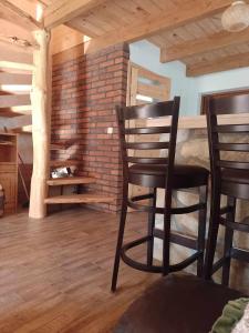 a room with two black chairs and a brick wall at Domek nad Stawem Siemuszowa in Tyrawa Wołoska