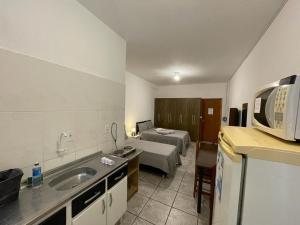 uma cozinha com um lavatório e uma cama num quarto em Studio 11 - Amplo Studio 2km da Vila Germânica em Blumenau