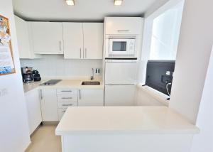 マルベーリャにあるSkol 302 Super One-bedroom Duplex with Sea Viewsの白いキッチン(白いキャビネット、電子レンジ付)