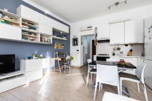 una cucina e una sala da pranzo con armadi bianchi e tavolo di Rogoredo - Exclusive Apartment a Milano