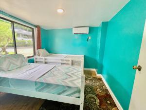 Habitación pequeña con cama y pared azul en Ngermid Oasis Cozy 2 BD 1BA Home, Scenic View, Secluded, Beautiful Location en Koror