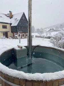 a hot tub in a snow covered yard with a house at Ferienwohnung Schulze Jonsdorf in Kurort Jonsdorf