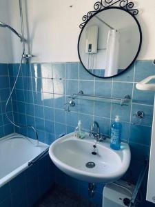 La salle de bains est pourvue de carrelage bleu, d'un lavabo et d'un miroir. dans l'établissement Personalunterkunft in Bad Bentheim bis 14 Personen, à Bad Bentheim