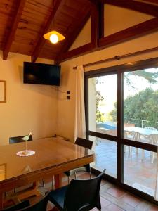 uma sala de jantar com uma mesa e uma porta de vidro deslizante em casas lago san roque em Villa Carlos Paz