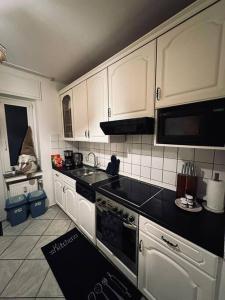 eine Küche mit weißen Schränken und schwarzen Arbeitsplatten in der Unterkunft Personalunterkunft in Rheine mit Balkon in Rheine