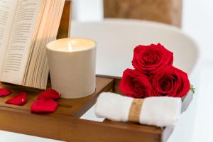 Eine Kerze und eine rote Rose und ein Buch in der Unterkunft PALAZZO RISTORI in Verona