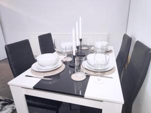 a dining room table with black chairs and a white table with glasses at Large 3 bed House Wolverhampton Families and Contractors in Wolverhampton