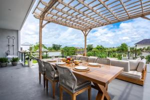 an outdoor dining room with a wooden table and chairs at Ozkar Villa Canggu in Canggu