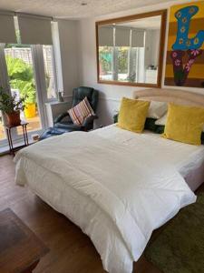 a bedroom with a large white bed with yellow pillows at Pond Cottage in Purley