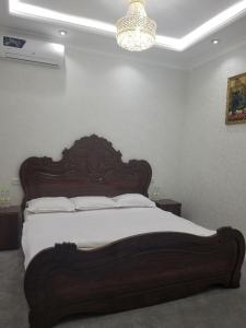 1 cama con cabecero de madera en un dormitorio en HOTEL OTA ABDUSALOM, en Samarkand