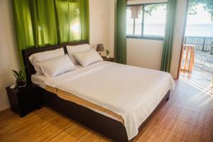 1 dormitorio con 1 cama grande y cortinas verdes en Nana's Beach Surigao, en Surigao