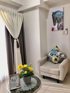 een woonkamer met een stoel en een tafel met bloemen bij 10F Central location & Near Airport in Davao City