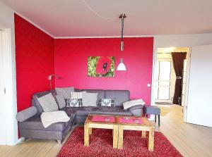 - un salon avec un canapé et un mur rouge dans l'établissement Apartmentvermittlung Mehr als Meer - Objekt 60, à Niendorf