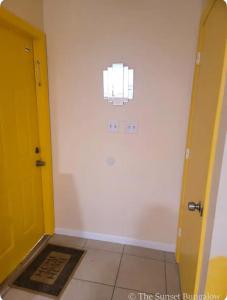 a hallway with a yellow door and a tile floor at The Sunset Bungalow in Naples