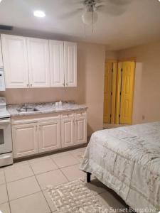 a kitchen with white cabinets and a bed in it at The Sunset Bungalow in Naples