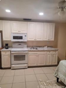 a kitchen with white cabinets and white appliances at The Sunset Bungalow in Naples