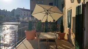 una mesa y una silla con una sombrilla en el balcón en Apartment Casa Marea, en Rovinj