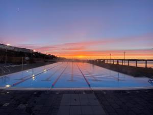 an empty swimming pool with the sunset in the background at Apartment Fernsicht in Borgarnes