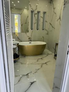a bathroom with a tub on a marble floor at Posh Spot on the beachfront sleeps 5 in Gqeberha