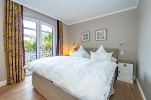 ein Schlafzimmer mit einem großen weißen Bett und einem Fenster in der Unterkunft Alva 1 in Westerland
