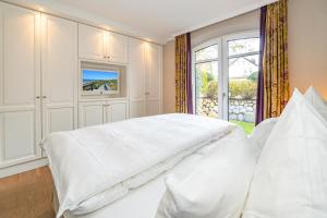 ein weißes Bett in einem Schlafzimmer mit einem Fenster in der Unterkunft Alva 1 in Westerland