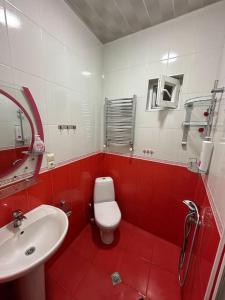 a red and white bathroom with a toilet and a sink at Comfortable House the city centr in Kutaisi