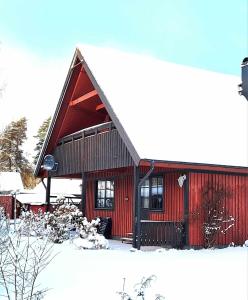 un granero rojo con nieve en el suelo en Vakantiewoning in Småland Zuid-Zweden, en Hjältevad