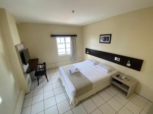 a bedroom with a bed and a desk and a chair at Hotel Premier in São Luís